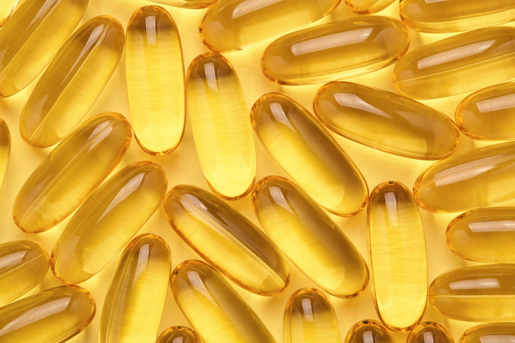 omega 3 softgels fish oil capsules yellow pills abstract background